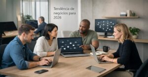 Grupo de quatro profissionais diversos reunidos em uma mesa de escritório analisando dados em um notebook, ilustrando o planejamento estratégico e a tendência de negócios para 2026.